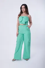 Conjunto de dos piezas color verde menta, compuesto por un top corto con breteles finos y detalle de lazo frontal, y un pantalón de corte recto tipo cargo con bolsillos laterales y cintura elástica.