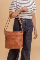 Bandolera mediana de cuero sintético color negro, con correa regulable, bolsillo frontal con cierre y compartimento principal.