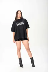 Remerón negro de corte oversize y mangas cortas, con estampa frontal difuminada estilo grafiti adornada con apliques de strass.