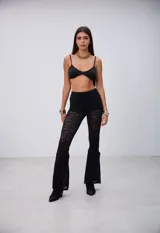 Pantalón de encaje negro, de corte ajustado en la parte superior y acampanado en la parte inferior.