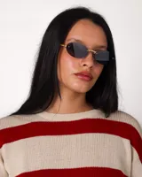 Lentes de sol ovalados con montura metálica dorada y cristales negros.