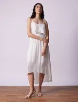 Vestido midi blanco de gasa bambula marca Lily Black, con escote redondo, breteles regulables y lazo de ajuste. Presenta una sobrecapa en el torso y un forro interno a tono. El largo de la espalda es mayor al largo delantero.