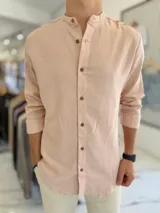 Camisa de lino color rosado, de manga larga, con cuello mao y cierre frontal de botones.
