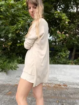Sweater color crema de tejido de punto con cuello en V y mangas largas.