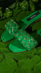 Sandalias negras con tiras trenzadas y cadena dorada.