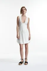 Vestido corto blanco con escote en V y detalle de puntilla en el escote.