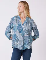 Blusa de gasa con estampado tipo paisley en tonos azules y blancos. Presenta cuello a la base con escote en V, mangas largas con presilla y botón para regular el largo.