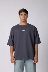 Remera oversize gris oscura con pequeño estampado frontal de la marca y mangas cortas amplias.