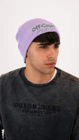 Gorro tipo beanie de punto acanalado en color lila, con bordado frontal en tonos verdes y blancos.