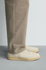 Zapatillas de piel estilo retro, color blanco crudo, con suela de goma con volumen en tono tostado y cierre de cordones.