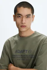 Remera de algodón verde militar con cuello redondo y estampado frontal con texto en color gris.