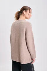 Cardigan de punto en color beige, con escote en V, cierre frontal de botones y mangas largas con puños acanalados.