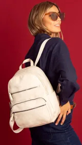 Mochila color marrón claro de símil cuero con bolsillos frontales con cierre. Tiene asa de mano rígida y correas regulables.