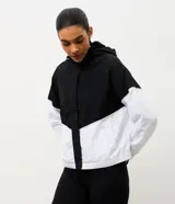 Campera rompeviento deportiva con diseño bicolor en negro y blanco. Presenta capucha con cordón ajustable, cierre frontal y puños elásticos.