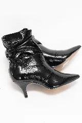 Bota corta de charol negro con efecto arrugado en la caña, punta fina y taco bajo tipo kitten heel.