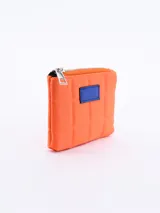 Monedero de diseño acolchado en color verde, con cierre metálico superior y detalle de parche rectangular en color amarillo en el frente.