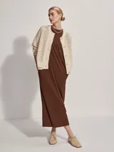 Cárdigan color crema de tejido de punto calado, con cuello redondo, cierre frontal con botones y corte holgado.