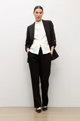Blazer recto color negro, con solapas de muesca, mangas largas con detalle de vuelta y bolsillos frontales ribeteados.