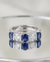Anillo de plata 925 con diseño de medio sin fin, engastado con cinco piedras de circonia alternadas entre blancas y azul zafiro.