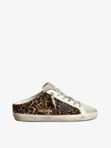 Zuecos Golden Goose modelo Super-Star Sabot, con diseño destalonado, confeccionados en pelo con estampado animal print de leopardo, detalles en cuero blanco y estrella lateral en cuero negro. Presentan suela con efecto desgastado característico de la marca.