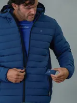 Campera acolchada Calvin Klein de color azul, con capucha, cierre frontal con cremallera y bolsillos laterales con cierre.