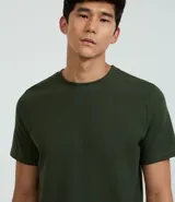 Remera de hombre, corte regular, color blanco hueso, con cuello redondo y manga corta. El tejido presenta una textura perforada vertical.