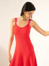 Vestido midi negro con breteles finos, escote recto y falda acampanada. Presenta detalles de ribete blanco en el escote y los breteles, y una línea vertical color ocre en el centro del frente.