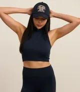 Top deportivo negro con cuello alto, escote halterneck y media cremallera. Confeccionado en poliamida seamless sin copa.