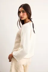 Saco de algodón tejido, color beige con mangas y detalles en blanco, escote en V y cierre frontal de botones.