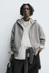 Sudadera de corte relajado confeccionada en tejido de algodón con interior afelpado. Presenta cierre frontal de cremallera, capucha con cuello subido, manga larga y acabados en rib.