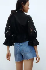Short de denim de algodón rígido, con diseño de tiro alto y cinco bolsillos. Presenta lavado azul clásico y dobladillo deshilachado.