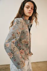 Blazer de jacquard de algodón con estampado floreado, cuello subido, manga larga y cierre frontal con botones. Presenta bolsillos de plastrón en el delantero, detalle de aplicación de lentejuelas, forro interior a tono y bajo asimétrico.