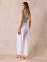 Pantalón blanco de lino con pretina ancha elastizada en punto smock, pierna ancha y ruedo con tajo.