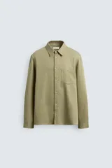Camisa de corte regular fit confeccionada en denim ligero con mezcla de lyocell, algodón y lino. Presenta cuello solapa, cierre frontal de botones, manga larga con puños abotonados y un bolsillo en el pecho.