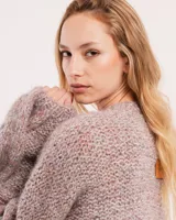 Buzo tejido a mano con lana, color rosa con motas de colores. Diseño oversized, largo entre la cintura y la cadera, con detalle de trenzas en las mangas.