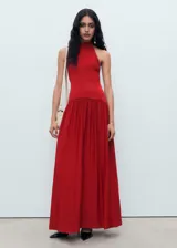 Vestido largo de punto fino color rojo, con diseño combinado, cuello halter y espalda descubierta. Presenta un corte ajustado en el torso y falda evasé con caída fluida.