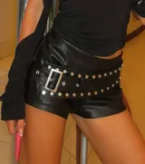 Short ajustado de cuero sintético negro, de tiro medio, con cinturón incorporado decorado con tachas metálicas redondas y hebilla cuadrada plateada.