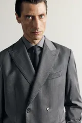 Blazer regular fit de Zara confeccionada en 100% lana, de color gris con diseño de rayas diplomáticas. Presenta cuello con solapas de pico, manga larga con botones en los puños, bolsillos con solapa en la cadera y bolsillo de vivo en el pecho. Cuenta con cierre frontal de botonadura cruzada.