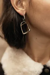 Aros colgantes plateados con dije en forma de estribo y argolla superior.