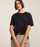 Blusa de manga corta confeccionada en algodón pima, con cuello redondo y diseño liso. Presenta un corte con el bajo ligeramente más extendido en la parte posterior.