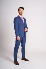 Ambo de corte entallado compuesto por saco de dos botones y pantalón de vestir a juego, en color azul. El saco presenta solapas clásicas y bolsillos con solapa, mientras que el pantalón tiene un corte recto y limpio.