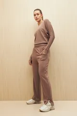 Buzo color beige de calce fluido, con cuello bote y mangas murciélago.