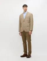 Blazer de medio forro, color marrón tostado, con solapas de muesca, cierre frontal de dos botones y bolsillos con solapa. Presenta silueta estructurada.