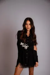 Camisa beige de corte amplio, con cuello clásico, cierre frontal con botones, mangas largas con puños abotonados y bordado floral en las mangas.