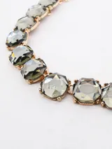 Collar corto tipo gargantilla compuesto por una cadena de eslabones dorados con cristales facetados oscuros engarzados.