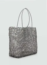 Bolso shopper grande de estilo trenzado, color gris, con dos asas superiores y detalle de charm metálico colgante.