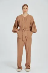 Mono largo color beige con cierre frontal, mangas abullonadas y cinturón con lazo.