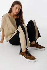 Zapatillas bajas con estampado animal print de leopardo, cordones negros y suela blanca.