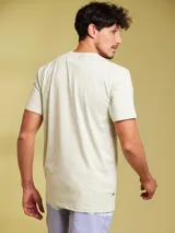 Remera de manga corta color arena, con cuello redondo y un bolsillo de parche en el pecho.