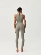 Top deportivo color gris con perforaciones decorativas en la parte delantera y trasera. Tejido Shape_Tech con tecnología performance, de sujeción media-alta, con copas extraíbles.